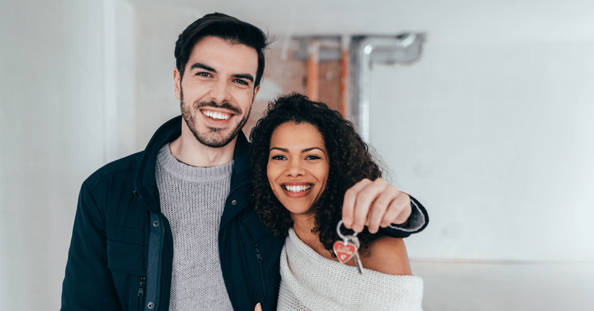 young couple holding keys after buying a new home