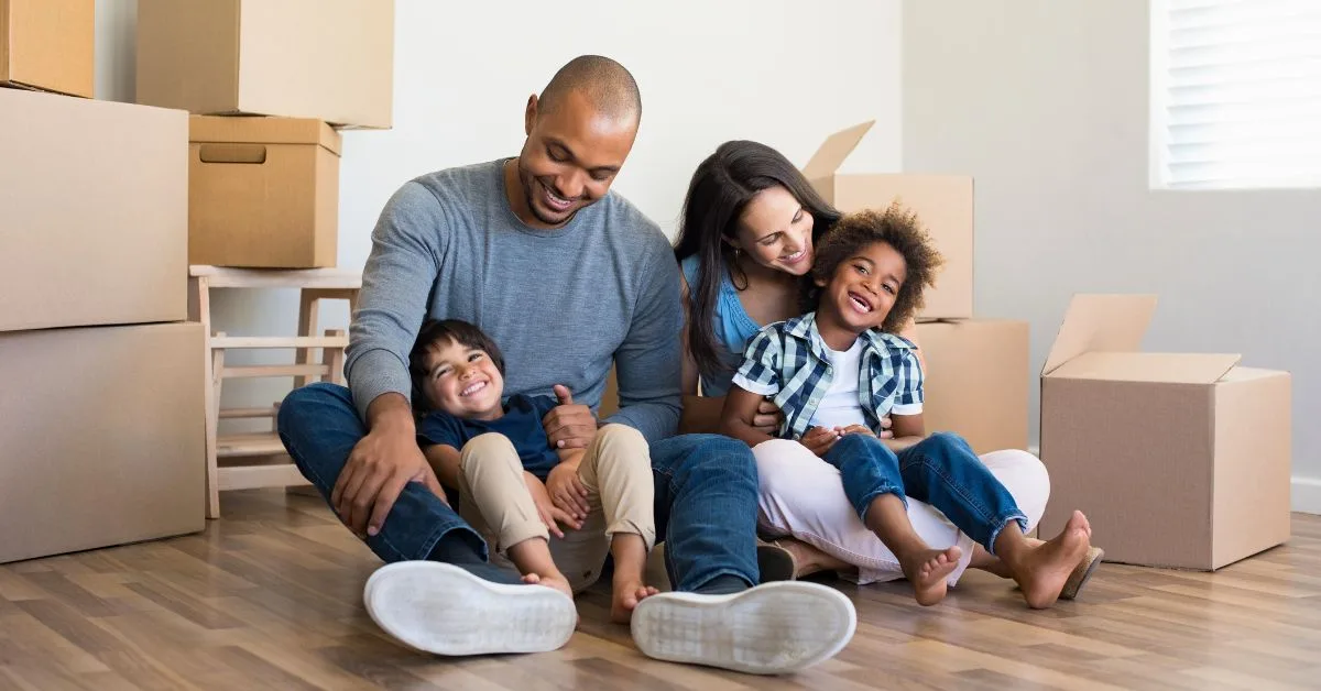 family sitting on floor in front of moving boxes