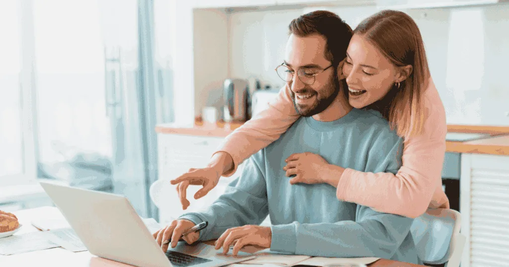 man and woman smiling in front of lapatop